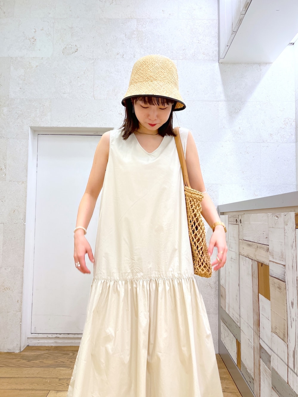 ベージュ系のバッグ、ホワイト系のワンピース、ブラック系のサンダルを着用したレディースの夏コーディネートの4枚目の写真