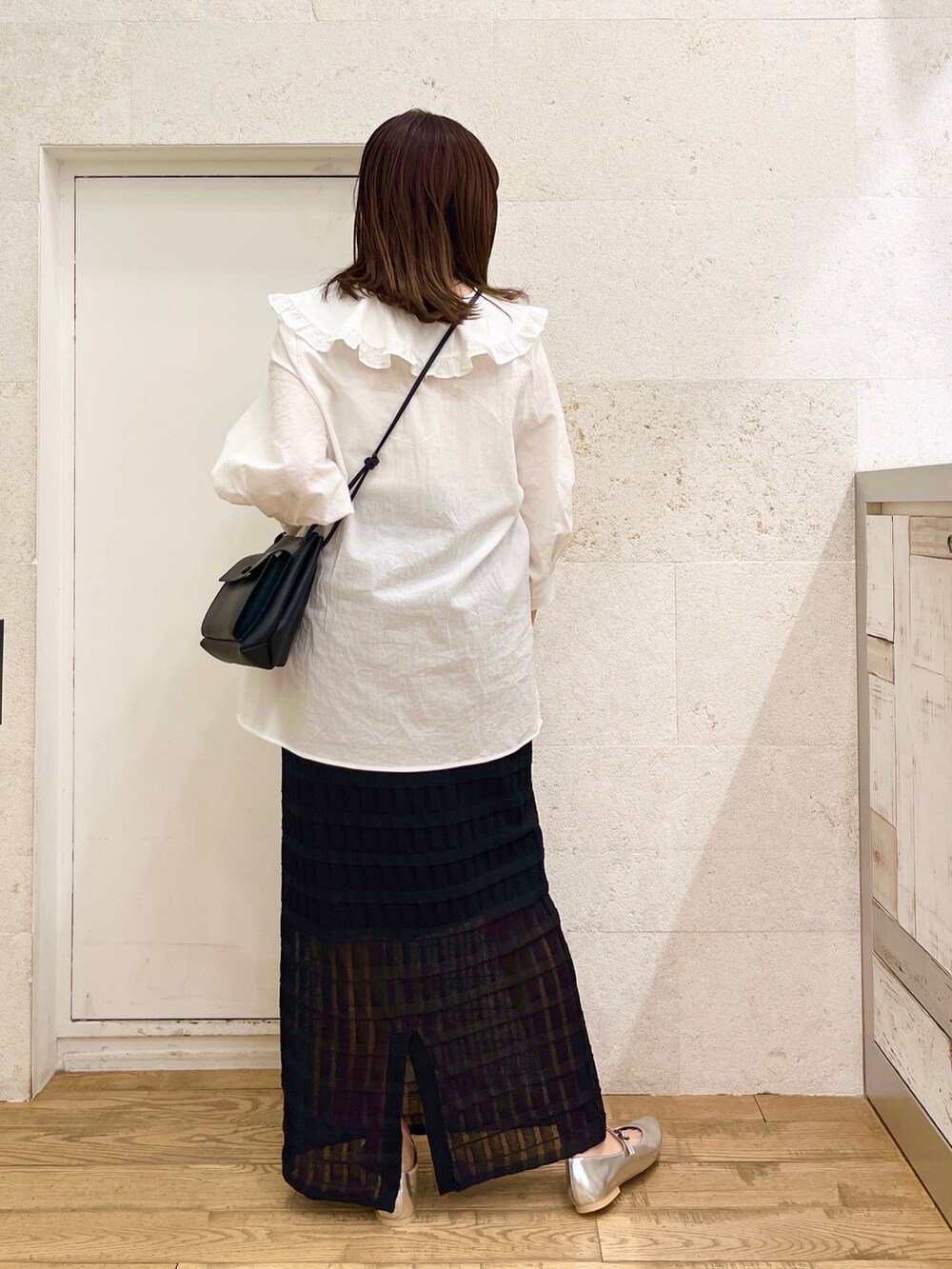 ホワイト系のトップス、ブラック系のスカート、ブラック系のバッグを着用したレディースの春コーディネートの5枚目の写真