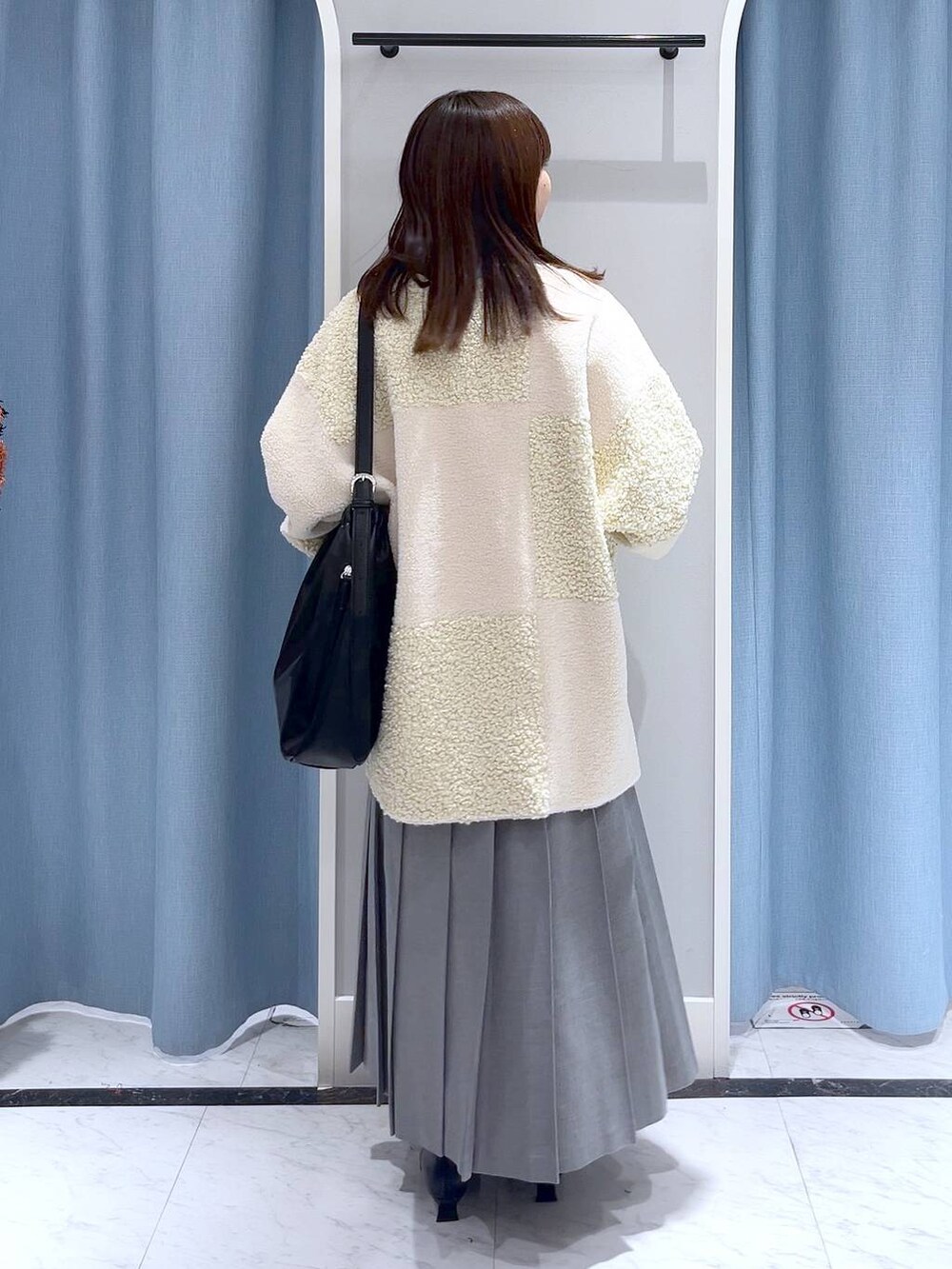 ブルー系のニット/セーター、ブラック系のブーツ、ブラック系のショルダーバッグを着用したレディースの冬コーディネートの2枚目の写真