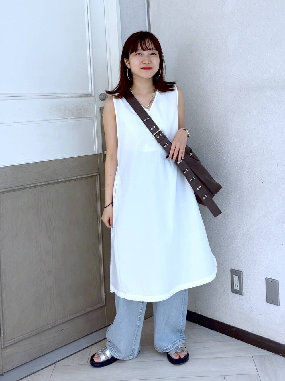 ホワイト系のTシャツ/カットソー、シルバー系のスニーカー、ブルー系のデニムパンツを着用したレディースの夏コーディネートの2枚目の写真