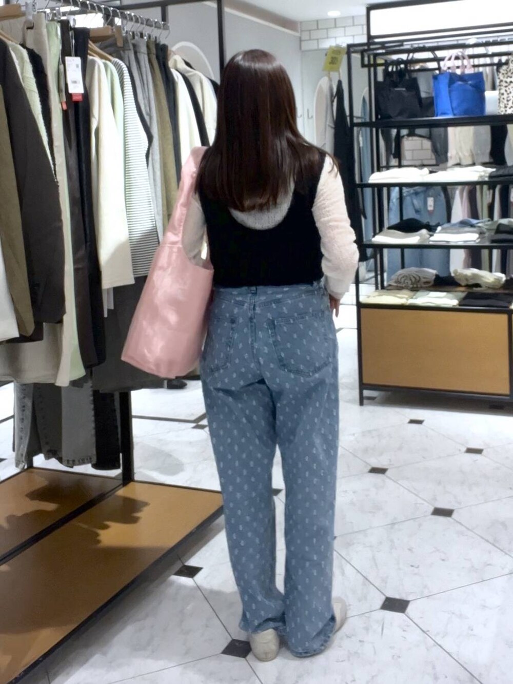ブルー系のデニムパンツ、ホワイト系のスニーカー、ブラック系のニット/セーターを着用したレディースの春コーディネートの3枚目の写真