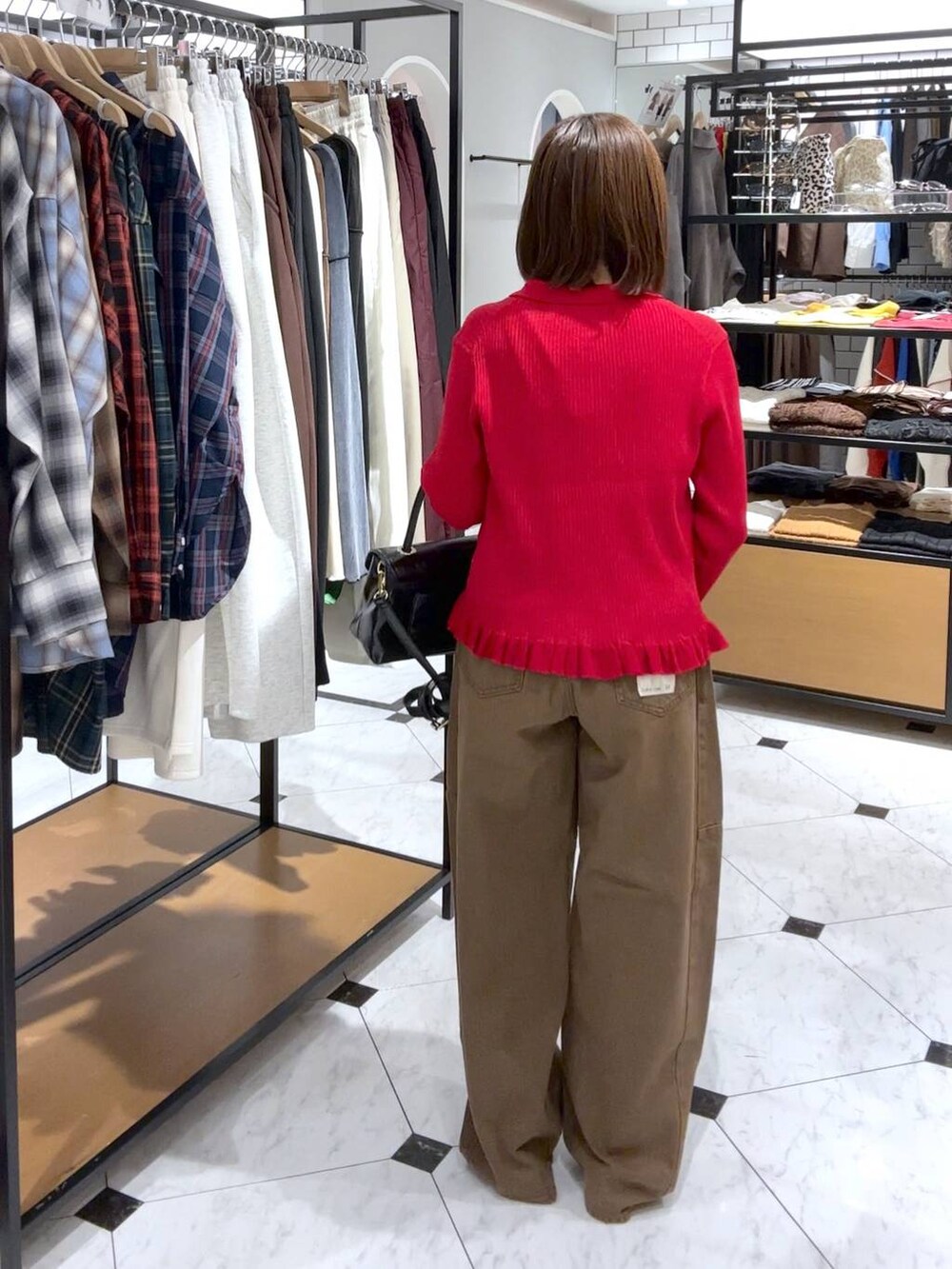 ブラウン系のデニムパンツ、ブラック系のボストンバッグ、ブラック系のパンプスを着用したレディースの秋コーディネートの2枚目の写真