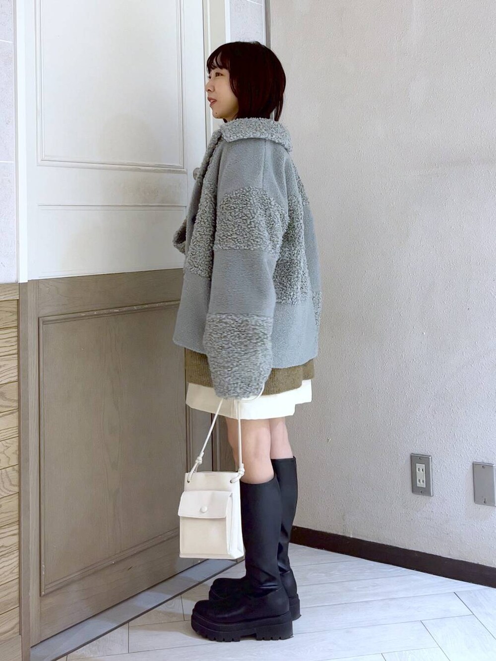 ベージュ系のニット/セーター、ホワイト系のショルダーバッグ、ブラック系のブーツを着用したレディースの冬コーディネートの2枚目の写真