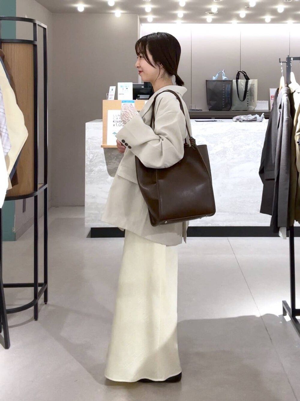 イエロー系のスカート、ブラック系のパンプス、ベージュ系のその他アウターを着用したレディースの春コーディネートの2枚目の写真