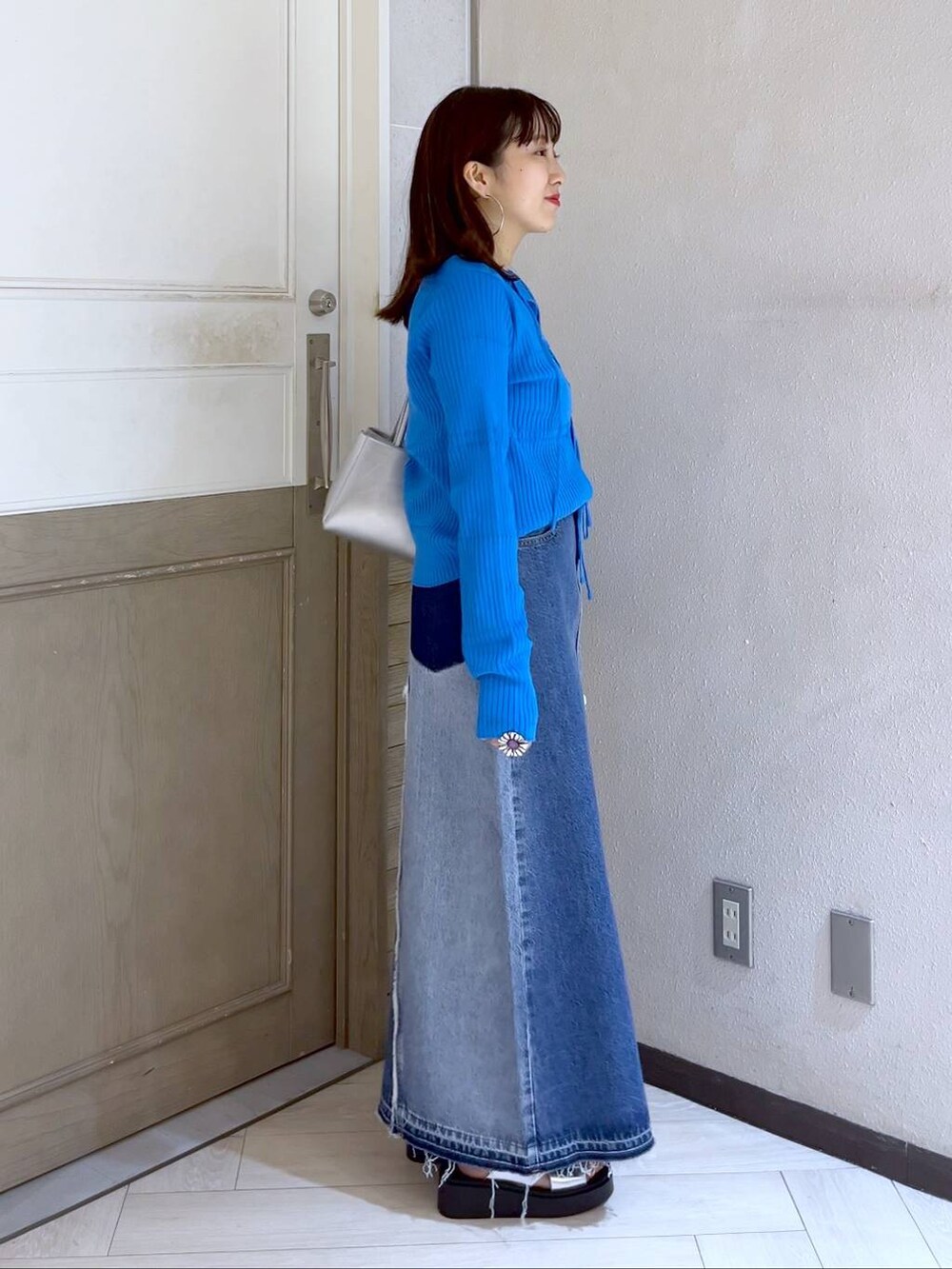 ブルー系のニット/セーター、シルバー系のサンダル、シルバー系のショルダーバッグを着用したレディースの夏コーディネートの2枚目の写真