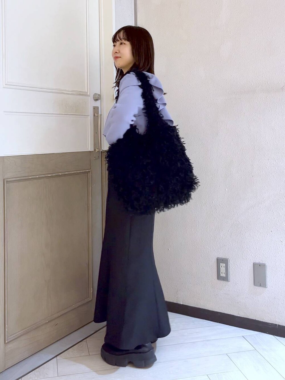 ブラック系のスカート、ブラック系のブーツ、パープル系のニット/セーターを着用したレディースの冬コーディネートの3枚目の写真