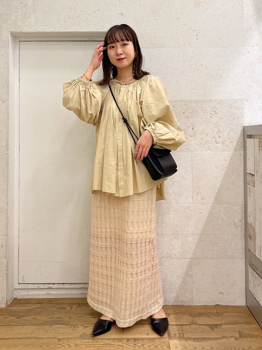 ブラウン系のシャツ/ブラウス、ホワイト系のバッグ、ブラック系のスカートを着用したレディースの春コーディネートの2枚目の写真