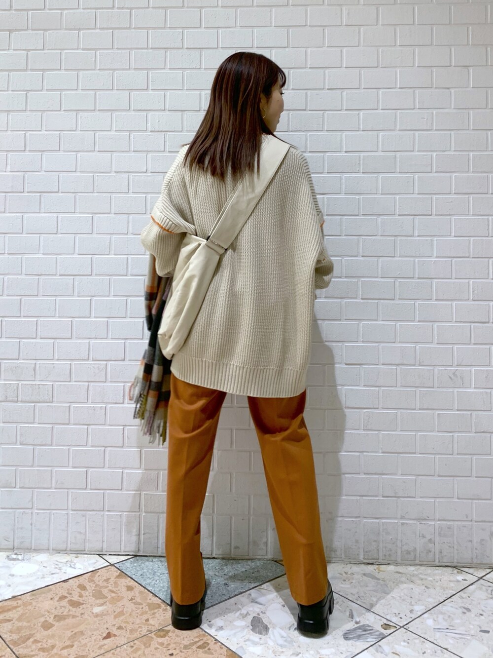 ブラウン系のニット/セーター、オレンジ系のパンツ、ホワイト系のバッグを着用したレディースの冬コーディネートの4枚目の写真