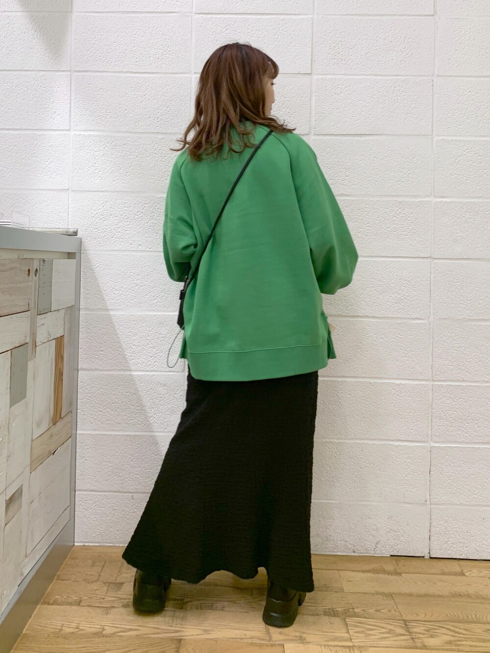 グリーン系のトップス、ブラック系のスカート、ブラック系のバッグを着用したレディースの秋コーディネートの3枚目の写真