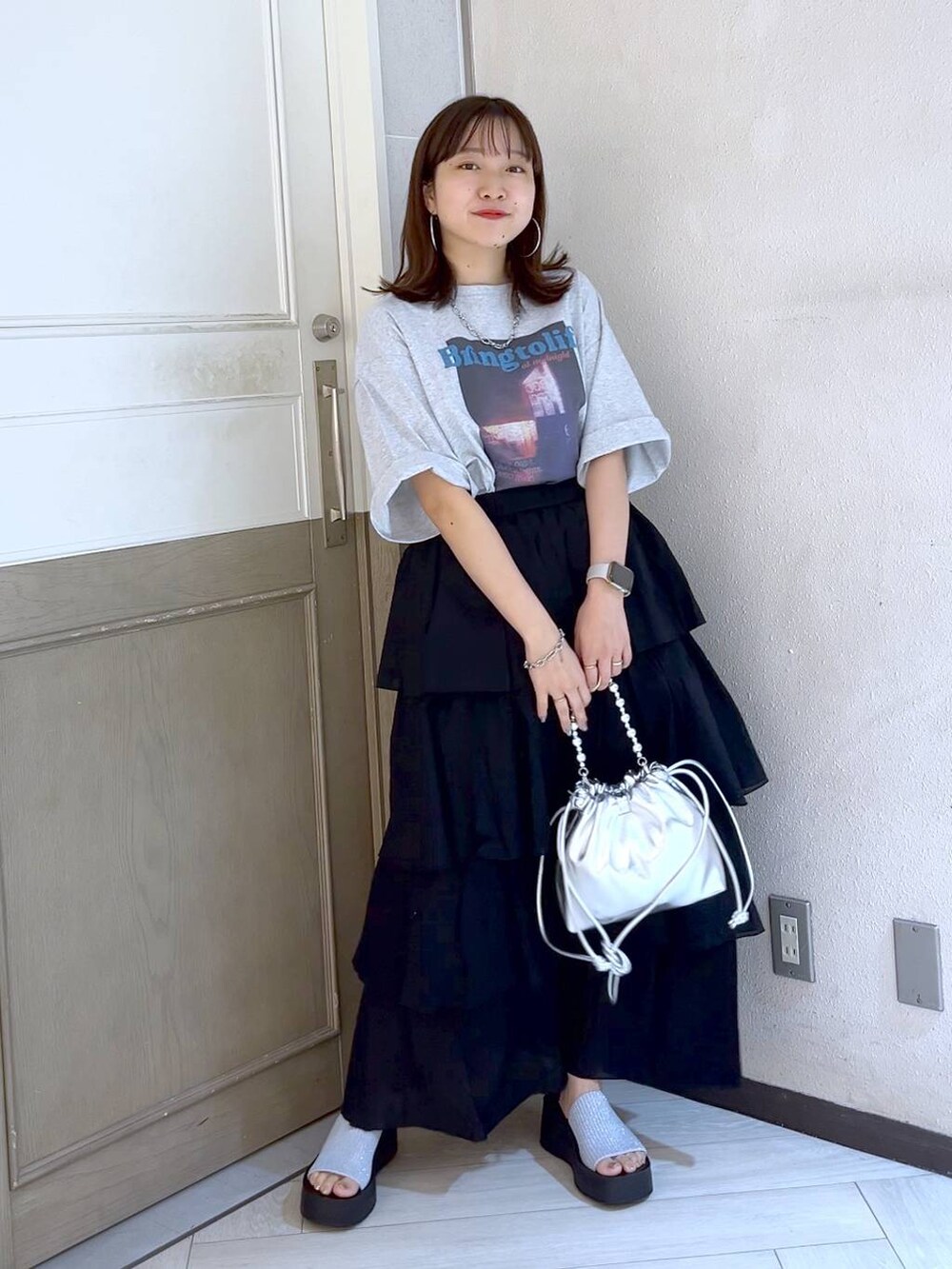 シルバー系のサンダル、シルバー系のショルダーバッグ、ブラック系のスカートを着用したレディースの夏コーディネートの3枚目の写真