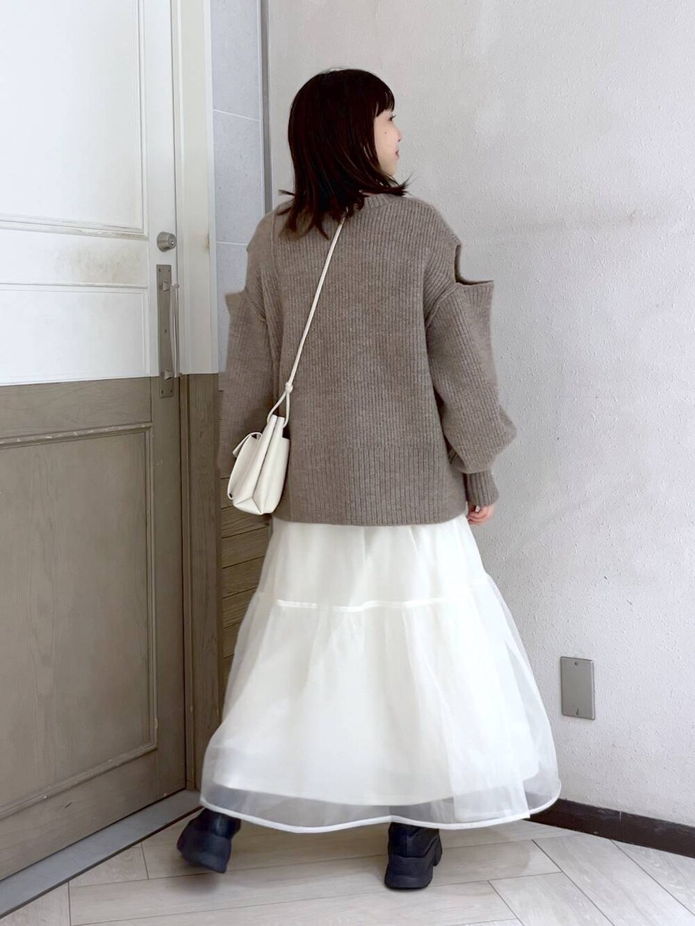 ホワイト系のショルダーバッグ、ブラック系のブーツ、ホワイト系のスカートを着用したレディースの秋コーディネートの5枚目の写真