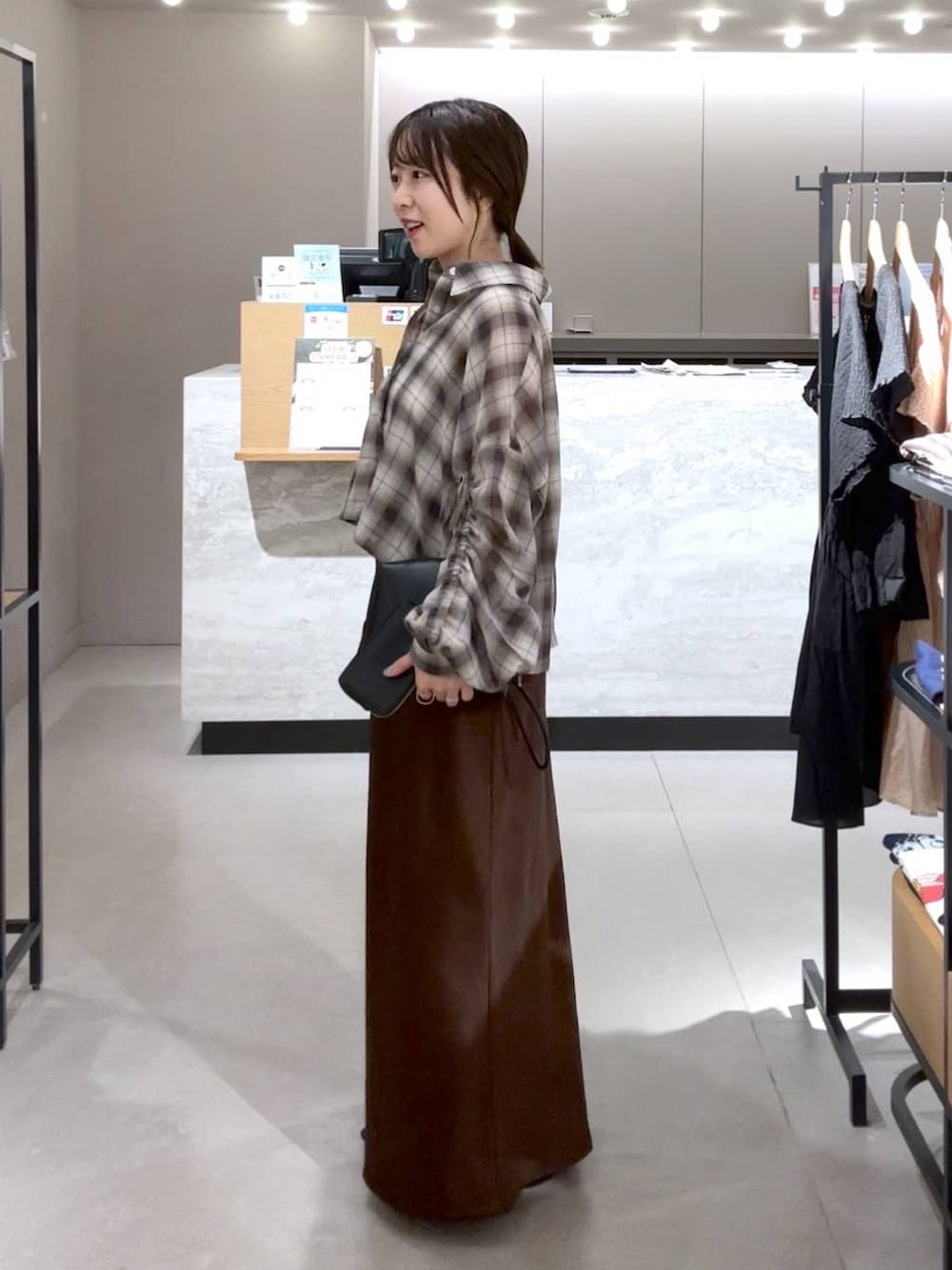ブラウン系のスカート、ブラック系のパンプス、ブラック系のトートバッグを着用したレディースの春コーディネートの3枚目の写真
