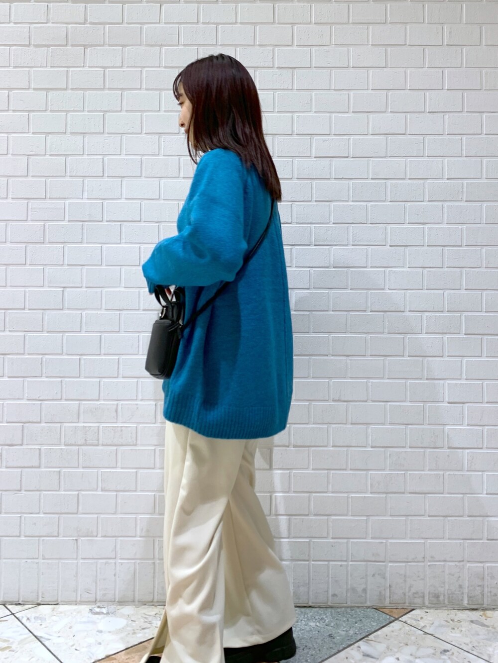 ブルー系のトップス、ブラック系のバッグ、ブラック系のブーツを着用したレディースの冬コーディネートの3枚目の写真