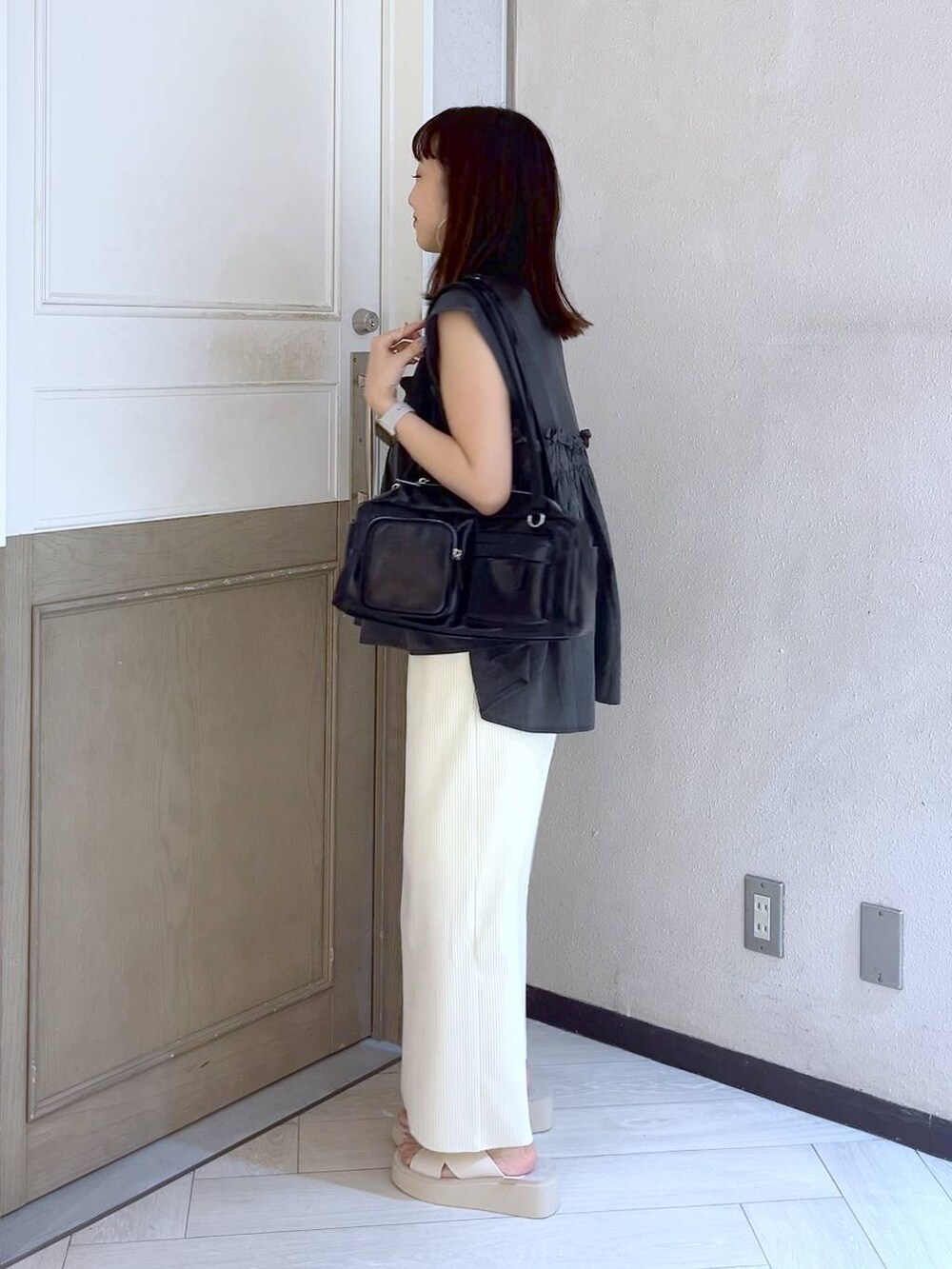 ホワイト系のスカート、ホワイト系のサンダル、ブラック系のボストンバッグを着用したレディースの夏コーディネートの3枚目の写真