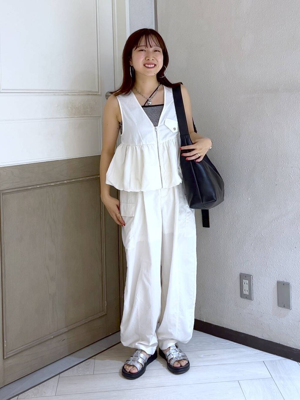 ホワイト系のカーゴパンツ、ホワイト系のベスト、シルバー系のスニーカーを着用したレディースの夏コーディネートの2枚目の写真