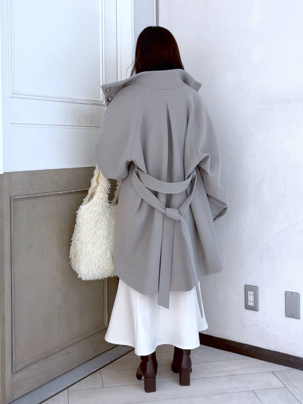 ホワイト系のスカート、ホワイト系のその他アウター、ブラウン系のパンプスを着用したレディースの冬コーディネートの3枚目の写真