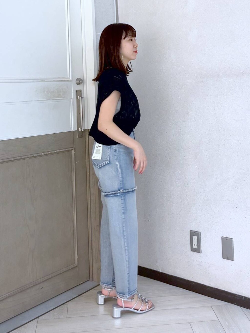 シルバー系のサンダル、ブルー系のデニムパンツ、ブラック系のニット/セーターを着用したレディースの夏コーディネートの3枚目の写真