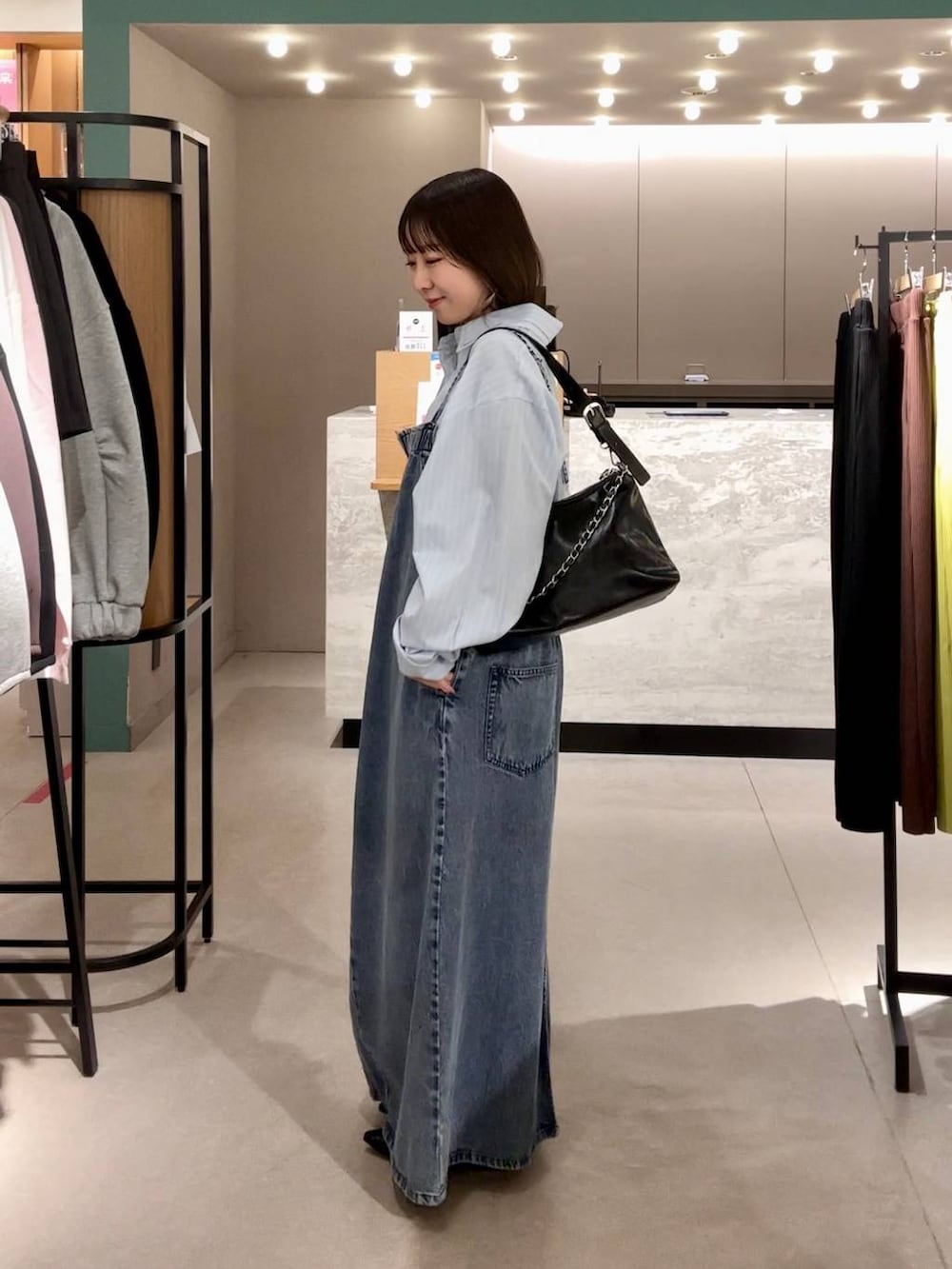 ブラック系のパンプス、ブラック系のショルダーバッグ、ブルー系のワンピースを着用したレディースの冬コーディネートの2枚目の写真