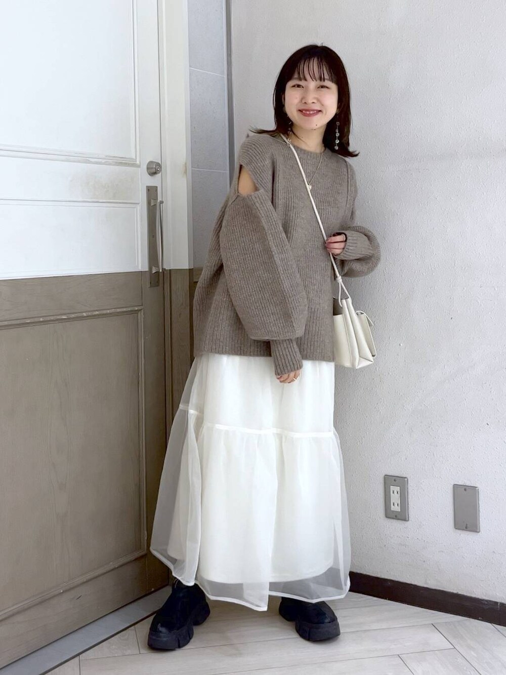 ホワイト系のショルダーバッグ、ブラック系のブーツ、ホワイト系のスカートを着用したレディースの秋コーディネートの3枚目の写真
