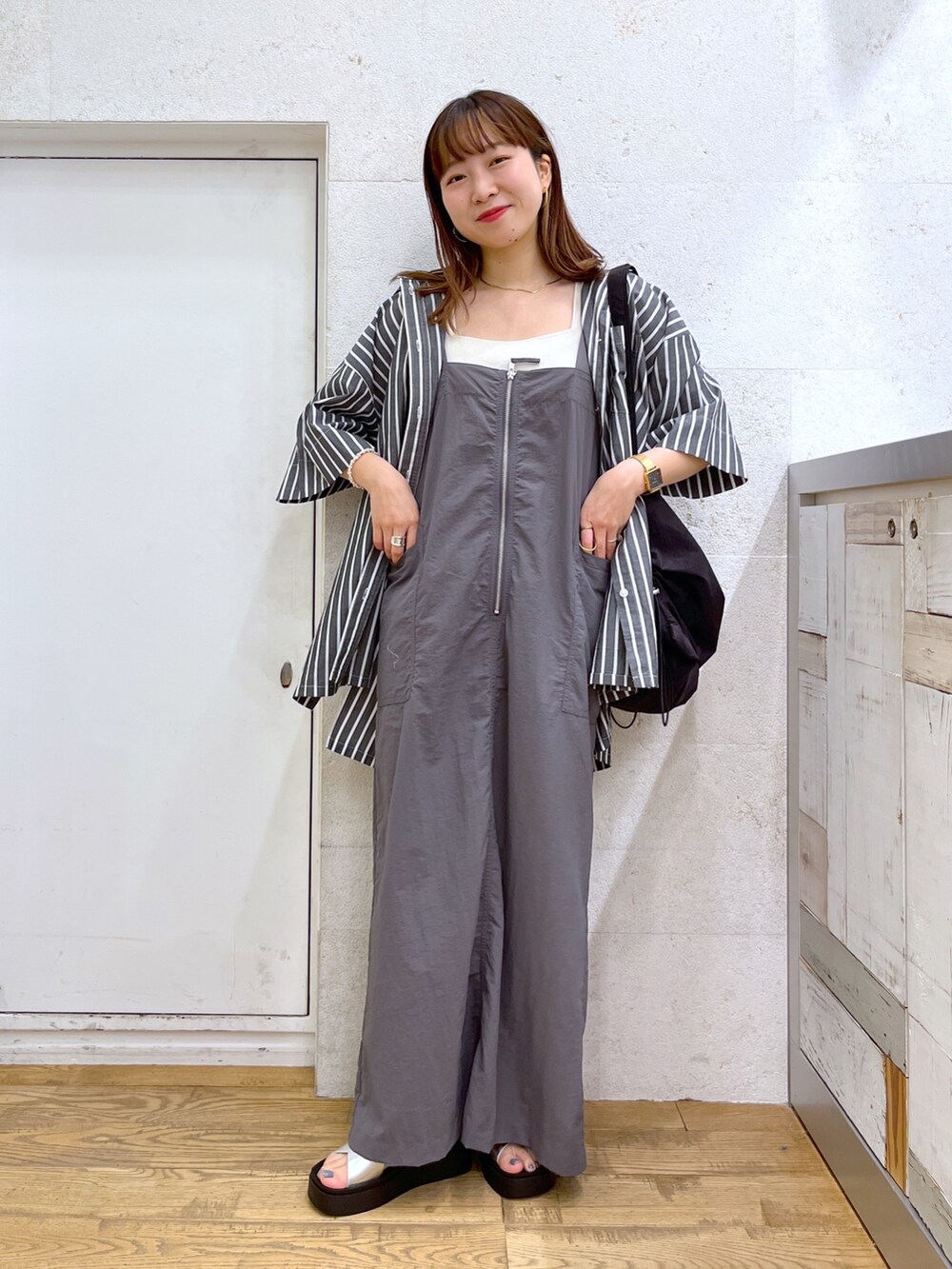 グレー系のワンピース、ブラック系のトップス、ブラック系のショルダーバッグを着用したレディースの夏コーディネートの3枚目の写真