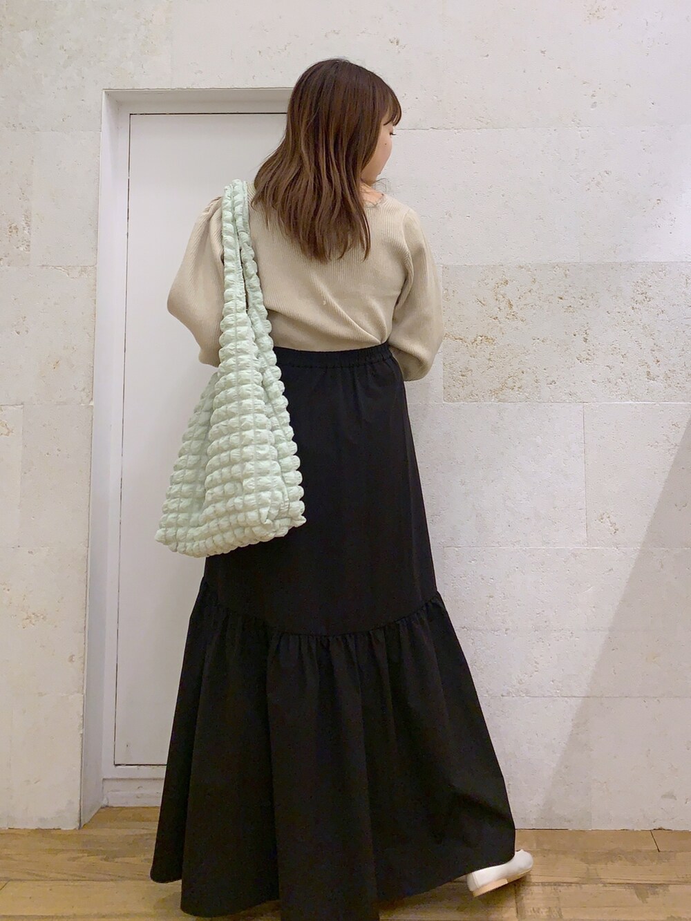 ホワイト系のトップス、ブラック系のスカート、ホワイト系のシューズを着用したレディースの春コーディネートの3枚目の写真