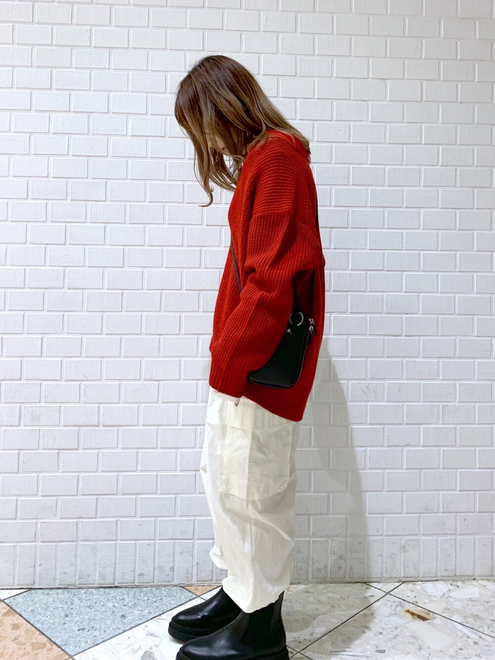 オレンジ系のトップス、ホワイト系のパンツ、ブラック系のバッグを着用したレディースの秋コーディネートの4枚目の写真