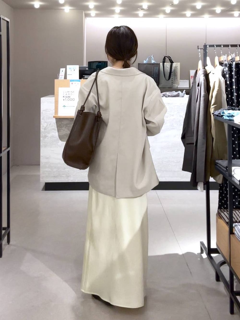 イエロー系のスカート、ブラック系のパンプス、ベージュ系のその他アウターを着用したレディースの春コーディネートの3枚目の写真