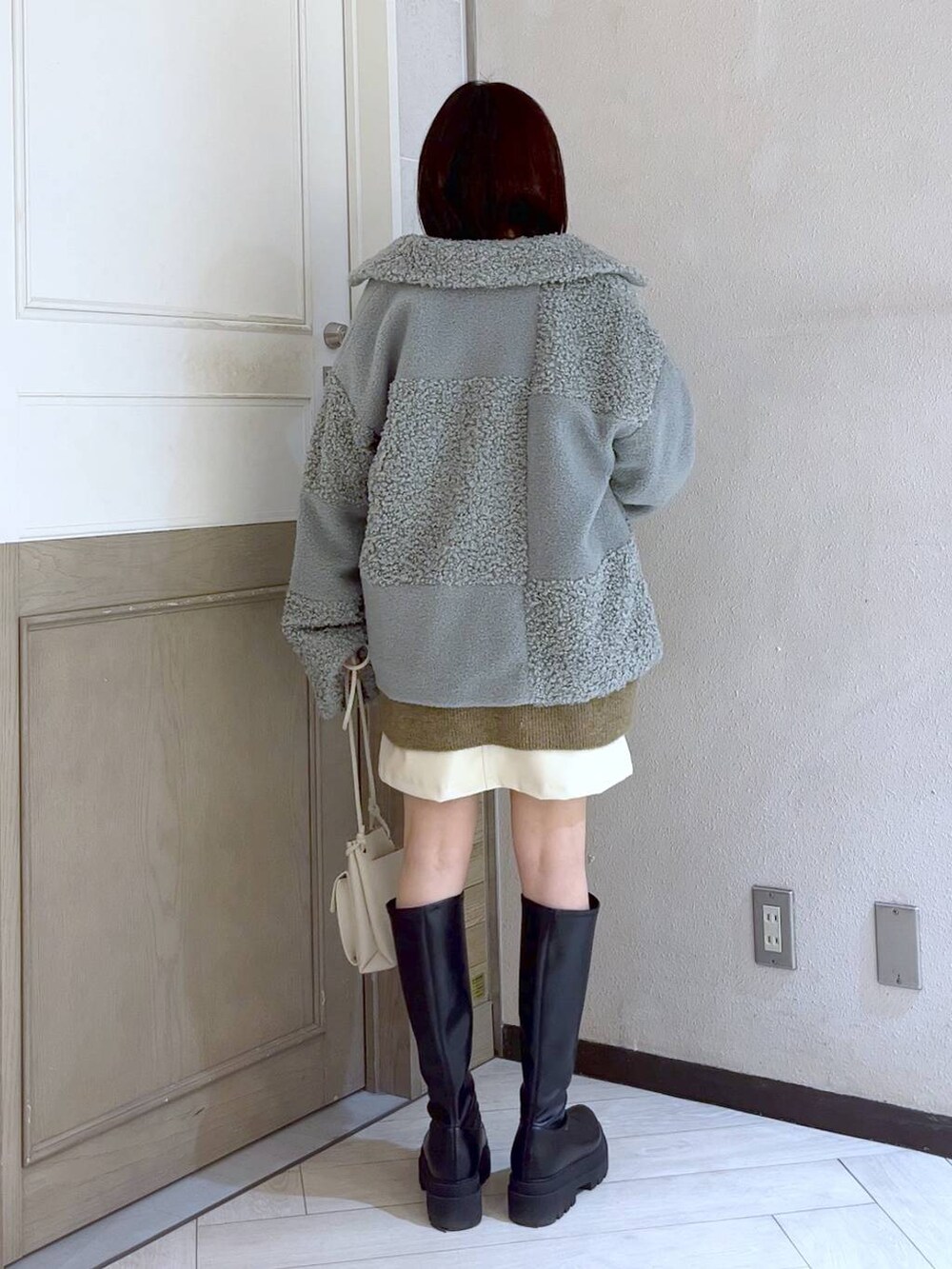 ベージュ系のニット/セーター、ホワイト系のショルダーバッグ、ブラック系のブーツを着用したレディースの冬コーディネートの3枚目の写真