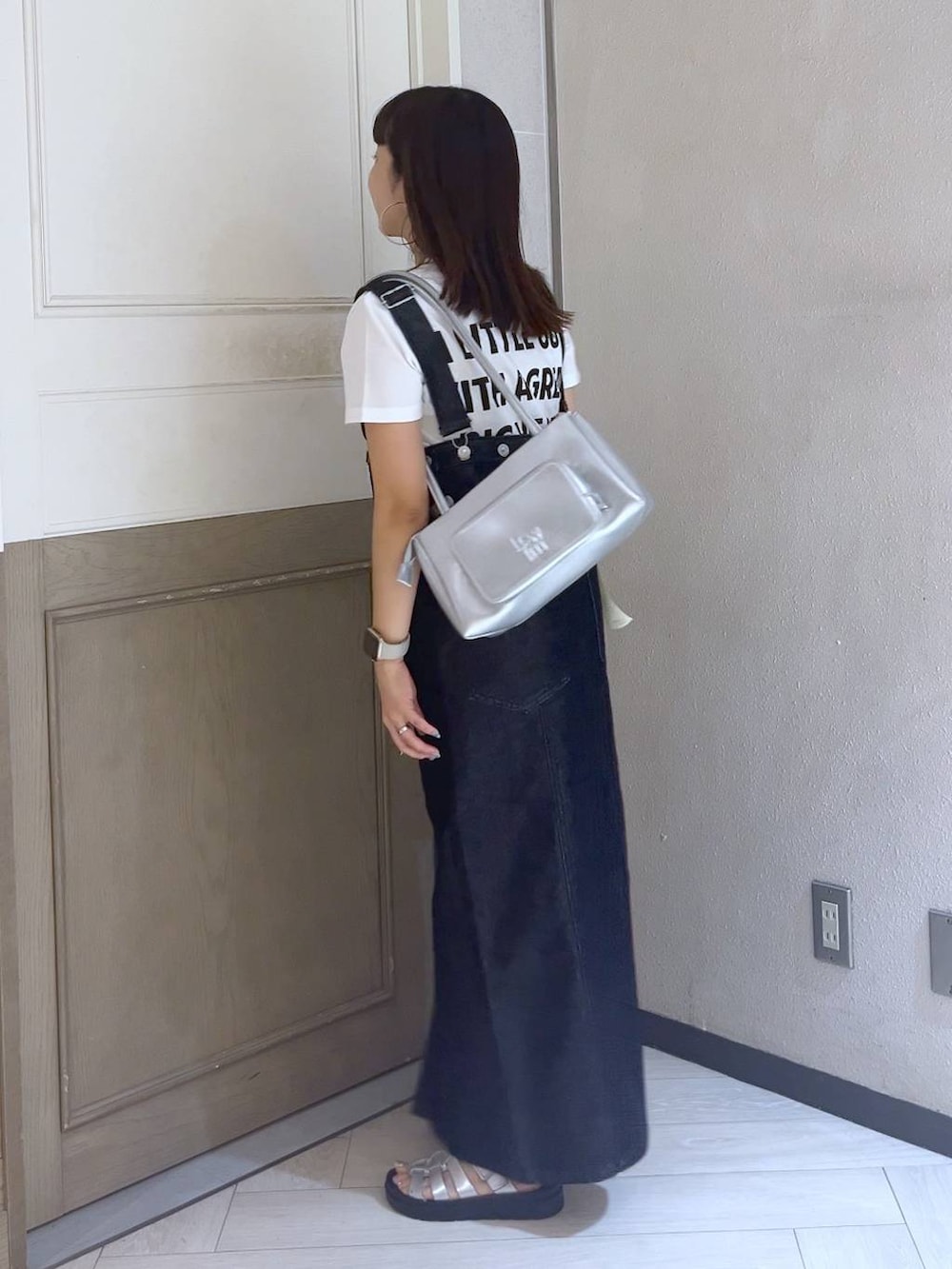 ブラック系のジャンパースカート、シルバー系のスニーカー、シルバー系のショルダーバッグを着用したレディースの夏コーディネートの3枚目の写真