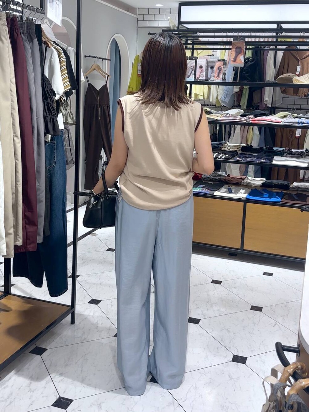 シルバー系のサンダル、ブルー系のその他パンツ、ブラック系のショルダーバッグを着用したレディースの夏コーディネートの3枚目の写真