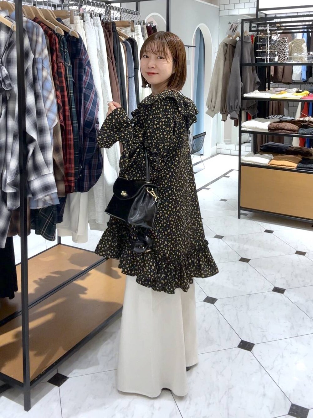 ホワイト系のスカート、ブラック系のボストンバッグ、ブラック系のパンプスを着用したレディースの秋コーディネートの2枚目の写真