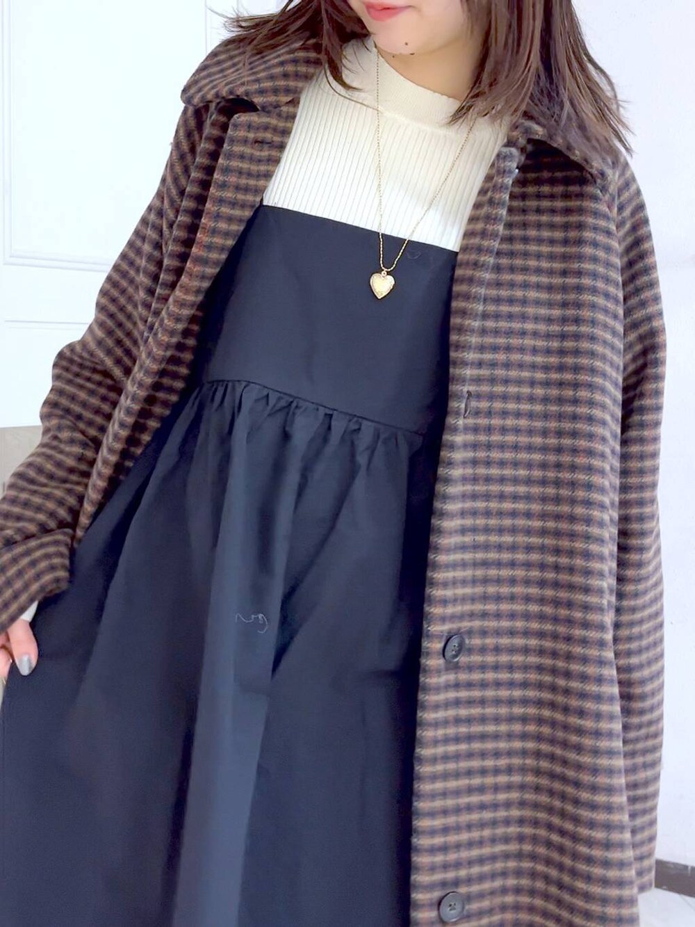 ブラウン系のノーカラーコート、ホワイト系のブーツ、ブラック系のワンピースを着用したレディースの冬コーディネートの5枚目の写真