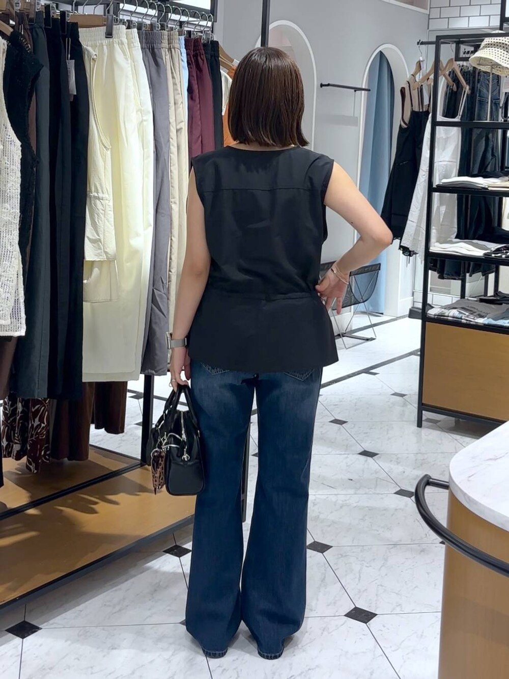 ホワイト系のTシャツ/カットソー、シルバー系のサンダル、ブラック系のショルダーバッグを着用したレディースの夏コーディネートの3枚目の写真