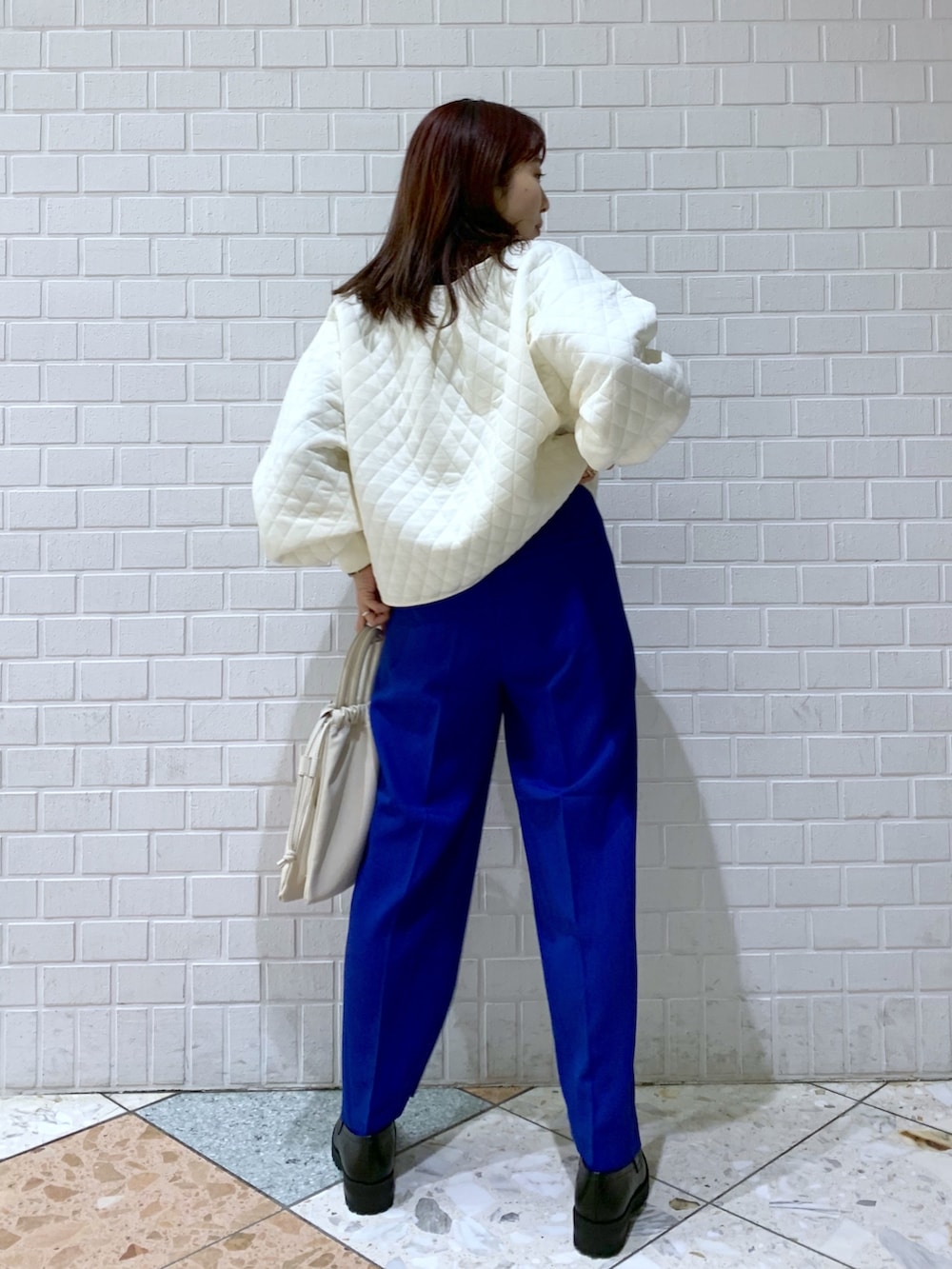 ホワイト系のトップス、ブルー系のパンツ、ホワイト系のショルダーバッグを着用したレディースの秋コーディネートの2枚目の写真