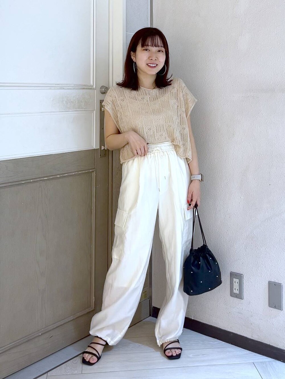 ホワイト系のカーゴパンツ、ブラック系のショルダーバッグ、ブラック系のサンダルを着用したレディースの夏コーディネートの2枚目の写真