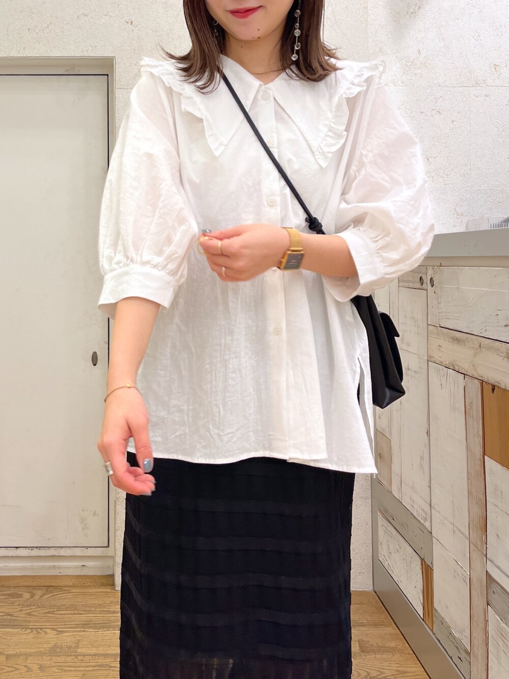 ホワイト系のトップス、ブラック系のスカート、ブラック系のバッグを着用したレディースの春コーディネートの3枚目の写真