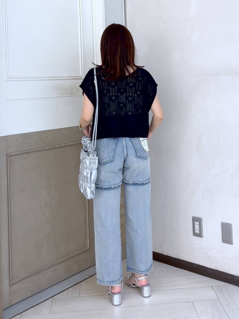 シルバー系のサンダル、ブルー系のデニムパンツ、ブラック系のニット/セーターを着用したレディースの夏コーディネートの5枚目の写真