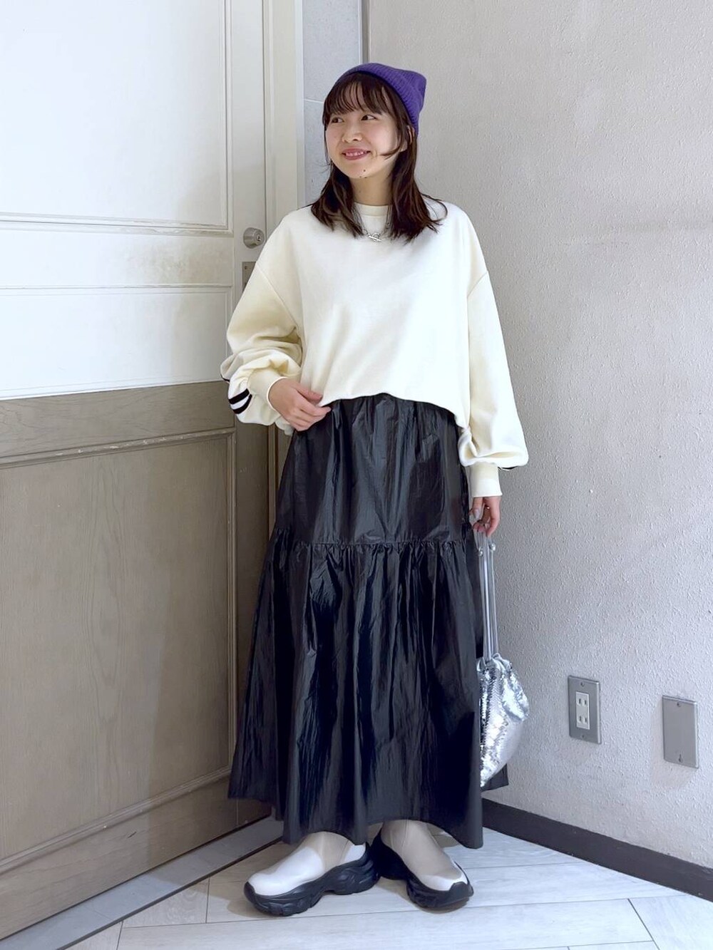 シルバー系のハンドバッグ、ホワイト系のスウェット、ホワイト系のブーツを着用したレディースの冬コーディネートの2枚目の写真