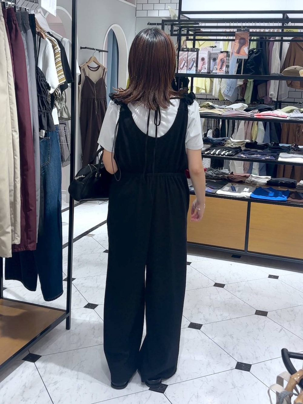 ブラック系のショルダーバッグ、シルバー系のTシャツ/カットソー、ブラック系のサロペット/オーバーオールを着用したレディースの夏コーディネートの2枚目の写真