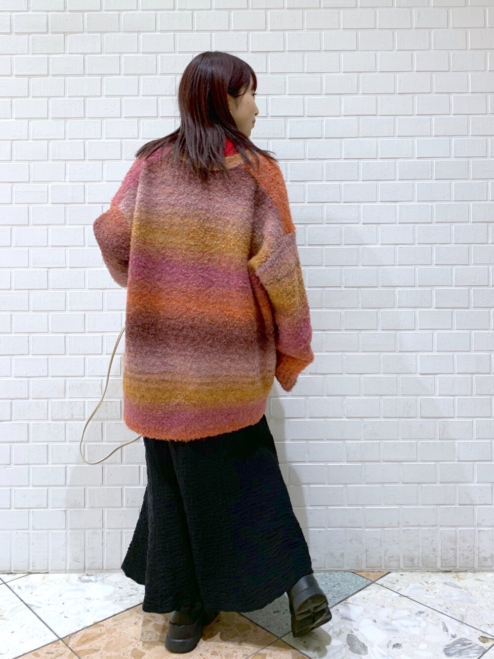 ピンク系のトップス、レッド系のニット/セーター、ブラック系のスカートを着用したレディースの冬コーディネートの2枚目の写真