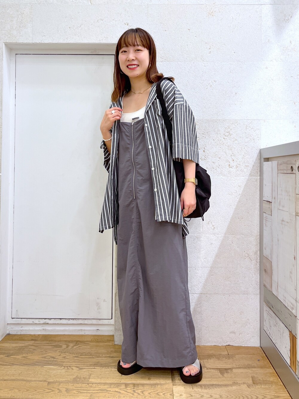 グレー系のワンピース、ブラック系のトップス、ブラック系のショルダーバッグを着用したレディースの夏コーディネートの2枚目の写真