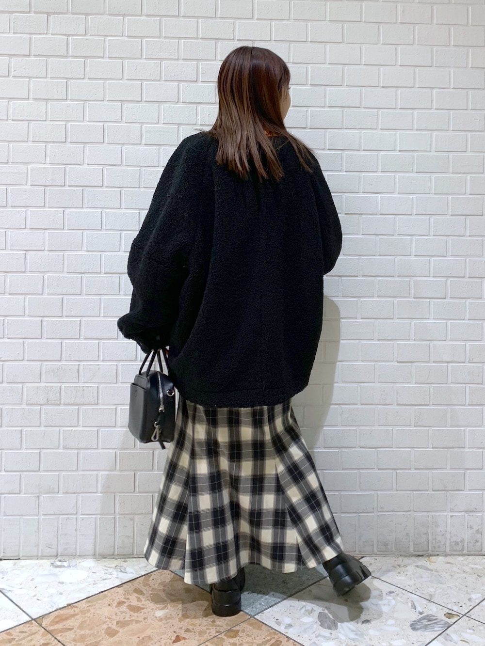 オレンジ系のトップス、ブラック系のスカート、ブラック系のジャケット/アウターを着用したレディースの冬コーディネートの2枚目の写真