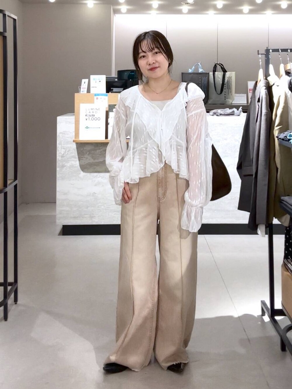 シルバー系のタンクトップ、ブラック系のパンプス、オレンジ系のデニムパンツを着用したレディースの春コーディネートの2枚目の写真