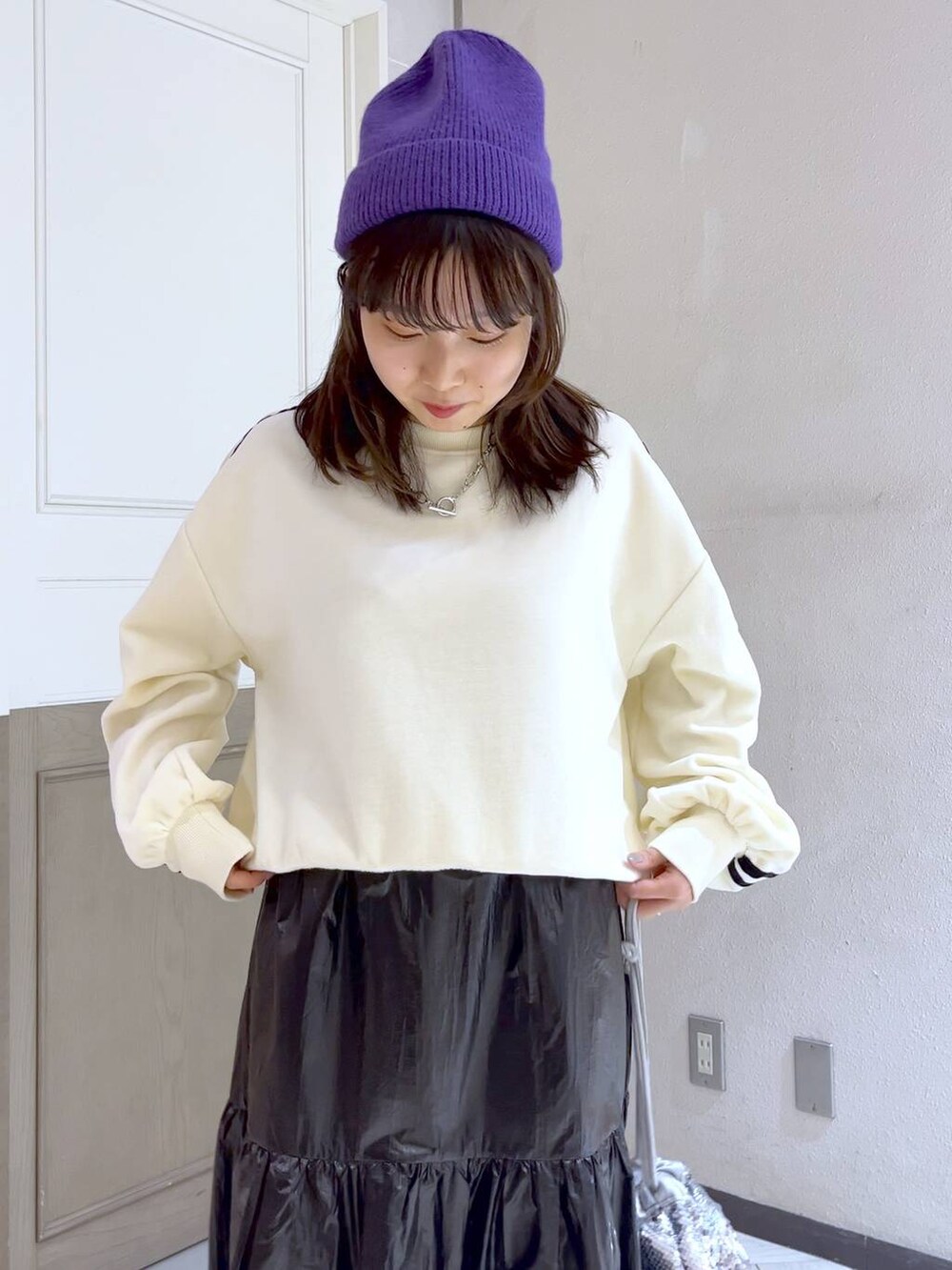 シルバー系のハンドバッグ、ホワイト系のスウェット、ホワイト系のブーツを着用したレディースの冬コーディネートの5枚目の写真