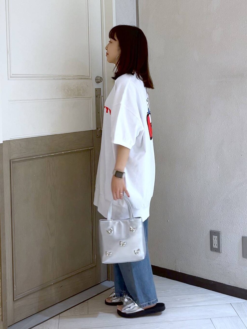 シルバー系のショルダーバッグ、ブルー系のデニムパンツ、シルバー系のサンダルを着用したレディースの夏コーディネートの3枚目の写真