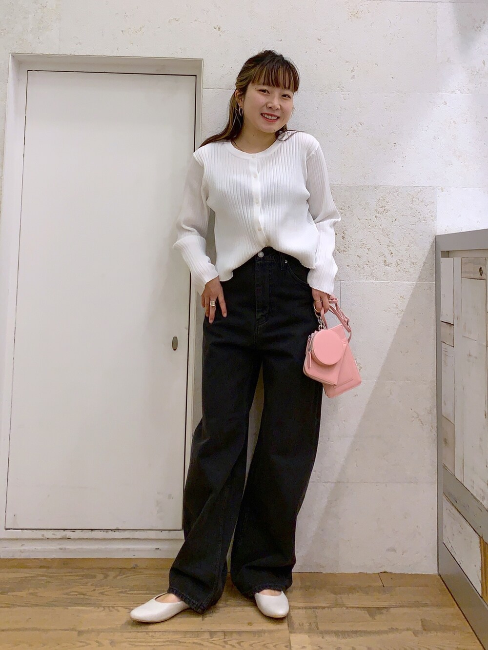 ホワイト系のトップス、ブラック系のパンツ、ピンク系のショルダーバッグを着用したレディースの春コーディネートの2枚目の写真