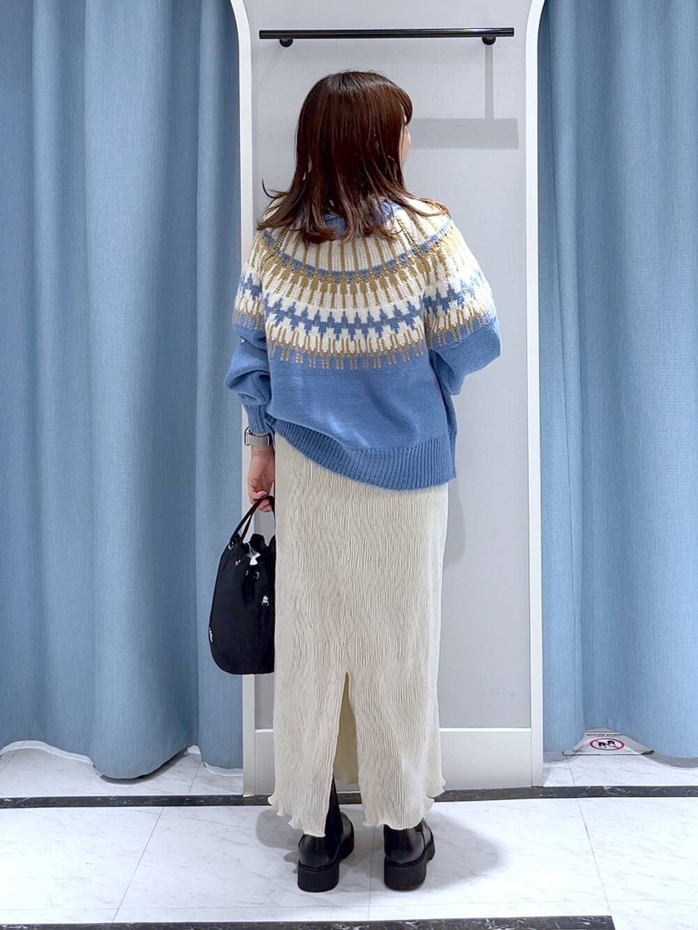 ブラック系のブーツ、ホワイト系のスカート、ブラック系のハンドバッグを着用したレディースの冬コーディネートの4枚目の写真