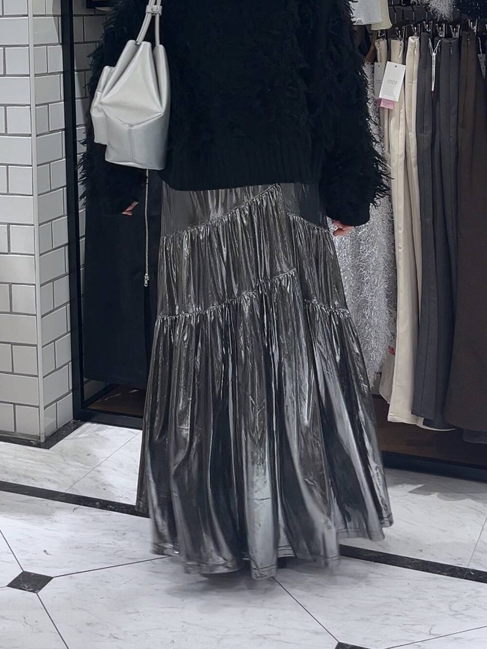 シルバー系のショルダーバッグ、ブラック系のブーツ、グレー系のスカートを着用したレディースの冬コーディネートの3枚目の写真