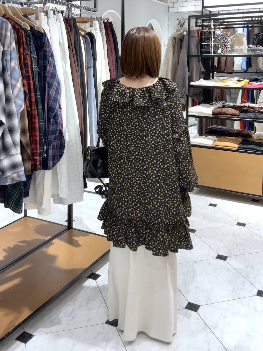 ホワイト系のスカート、ブラック系のボストンバッグ、ブラック系のパンプスを着用したレディースの秋コーディネートの3枚目の写真