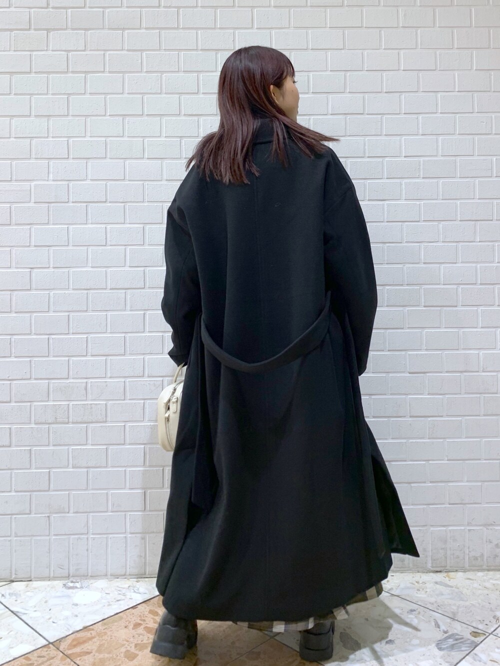 ブラック系のジャケット/アウター、ブルー系のトップス、ブラウン系のスカートを着用したレディースの冬コーディネートの4枚目の写真